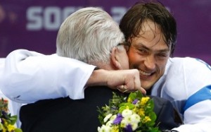 Teemu Selanne da Finlândia (8) abraça o apresentante depois de receber a sua medalha de bronze, logo após o jogo de hóquei no gelo masculino nos Jogos Olímpicos de Inverno de 2014. (AP Photo / Julio Cortez)