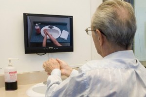 O voluntário Larry Lovas a lavar as mãos, enquanto segue as instruções no ecrã de um laboratório de Alzheimer em Toronto. Foto de arquivo: THE CANADIAN PRESS/Adrian Wyld