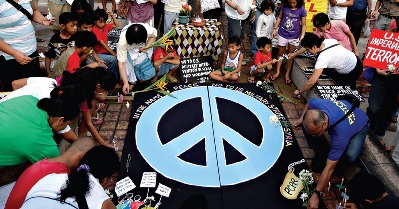 Filipinos põem flores junto a símbolo de paz num protesto em Manila contra um ataque na Síria