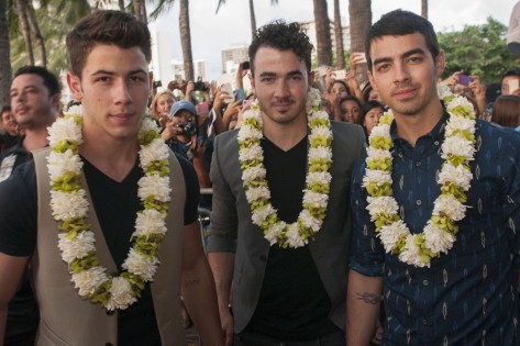 Nick, Kevin e Joe dos Jonas Brothers posam para uma foto depois de chegarem à estreia da quarta temporada de Hawaii Five-0, na Queen's Beach, em Waikiki, Havai - 26 de setembro de 2013. GETTY IMAGES/CBS/Norman Shapiro.