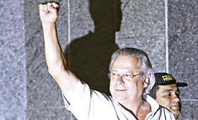 José Dirceu ergue o punho e saúda apoiantes antes de entrar na esquadra da polícia em São Paulo. (NACHO DOCE / REUTERS)