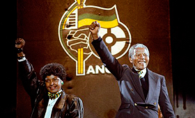 Nelson Mandela, com a então esposa Winnie, mostrando a famosa saudação de punho cerrado do Congresso Nacional Africano, num concerto no Estádio de Wembley, em Londres, Inglaterra, em 17 de abril de 1990. (THE CANADIAN Press)