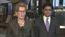 Kathleen Wynne fala aos jornalistas, acompanhada pelo ministro do Trabalho Yasser Naqvi