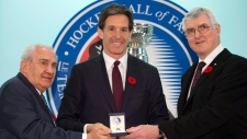 O nomeado para o Hockey Hall of Fame, Brendan Shanahan, recebe o seu anel da parte do presidente Pat Quinn (à direita) e do presidente do comité de seleção Jim Gregory, no Hall, em Toronto - 8 de novembro, 2013. (The Canadian Press / Frank Gunn)