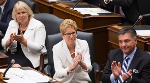 Kathleen Wynne, ao centro, sentada ao lado do ministro das Finanças Charles Sousa e da Presidente do Conselho do Tesouro Deb Matthews, aplaudem o tenente-Governador David Onley, quando ele apresenta o discurso do Trono no Queen’s Park em Toronto - 3 de julho de 2014. (The Canadian Press / Chris Young)