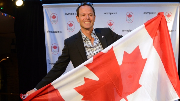 Jean-Luc Brassard segura uma bandeira canadiana depois de ser anunciado como o Chefe de Missão do Canadá para os Jogos Olímpicos do Rio 2016, em Montreal - 4 de dezembro de 2014. (The Canadian Press/Ryan Remiorz)