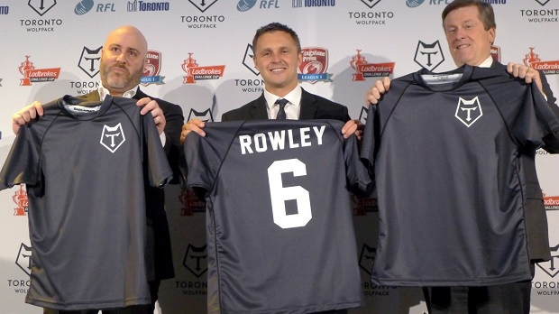 Eric Perez, fundador e CEO do Toronto Wolfpack, o treinador do Wolfpack, Paul Rowley, e o presidente de Toronto John Tory seguram a camisola da nova equipa da liga de râguebi, em Toronto - (The Canadian Press/Neil Davidson)